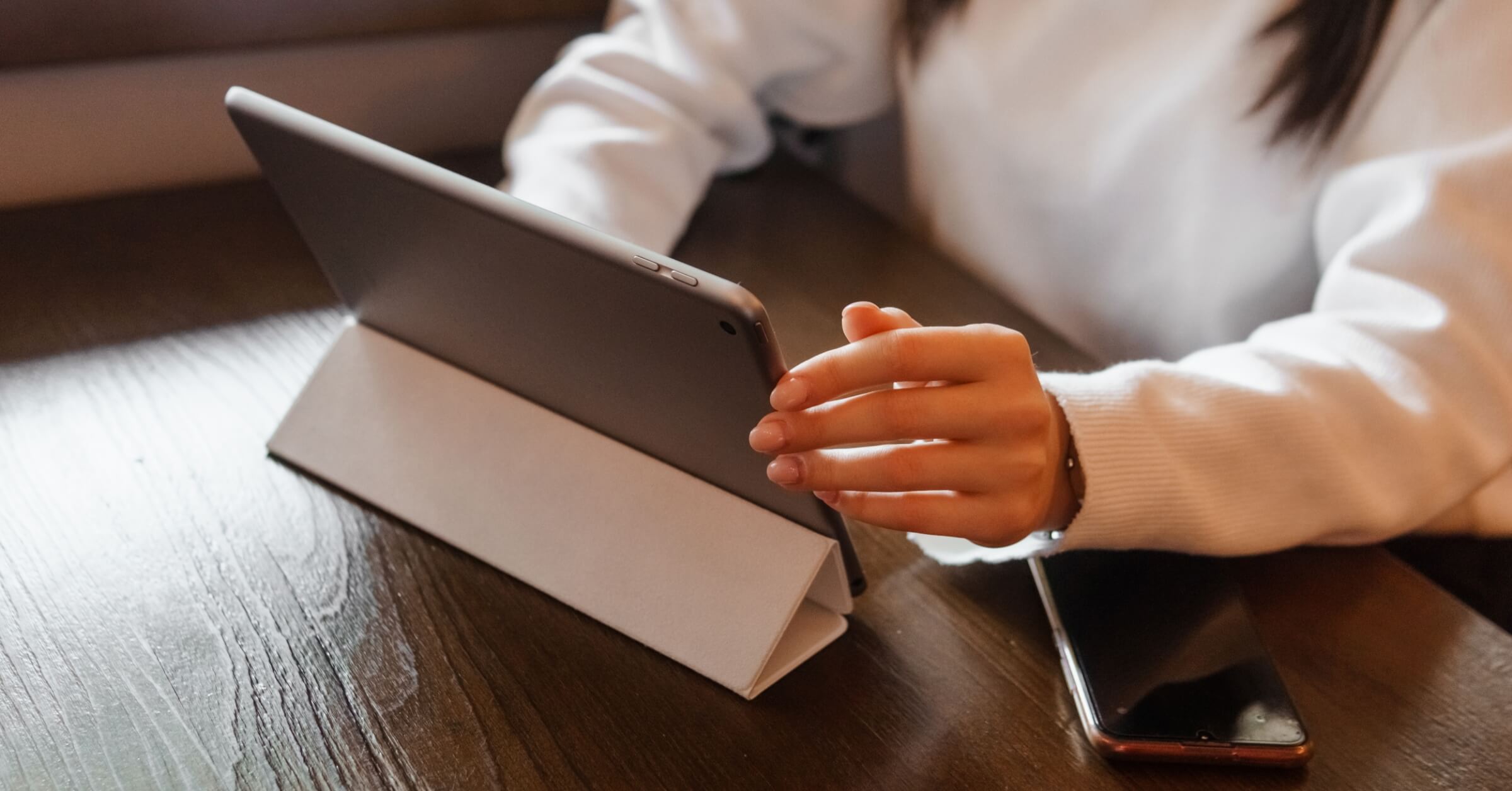 Kvinne i hvit genser jobber på en tablet