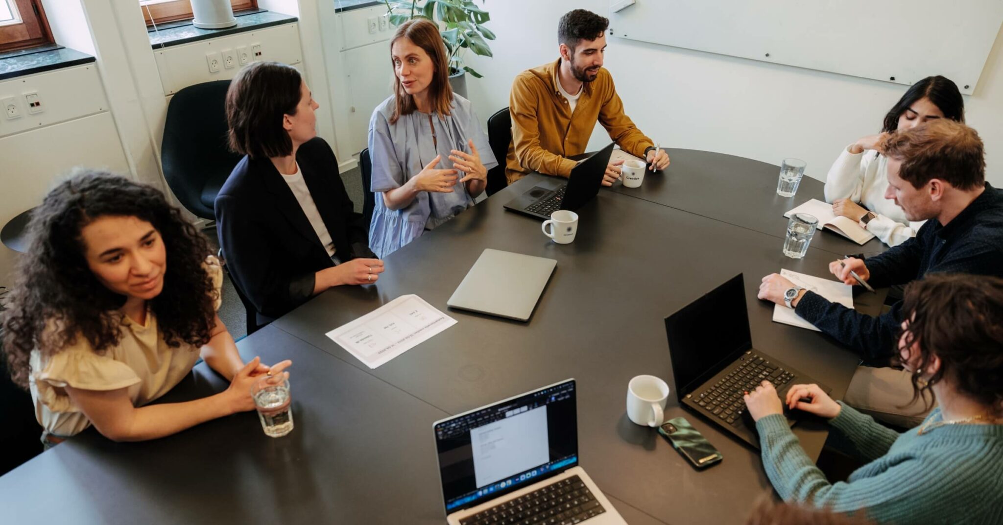 Unge mennesker samarbeider om et prosjekt rundt et tort, mørkt bord.