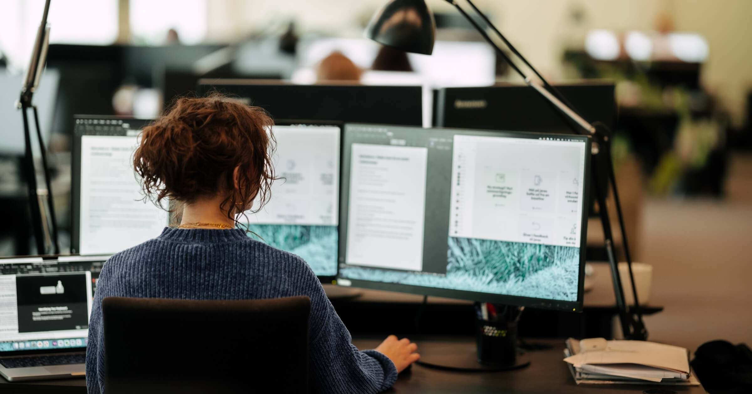 Kvinne jobber foran skjermer på et kontor
